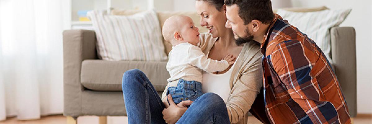 Seguros para Particulares - Familia con su bebe sentados en el suelo del salón de su casa jugando Seguros para Particulares - Familia con su bebe sentados en el suelo del salón de su casa jugando
